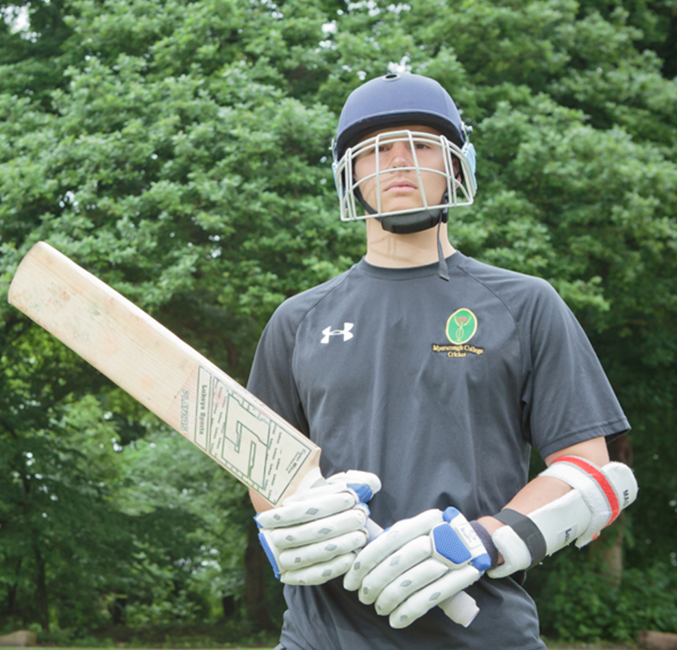 Myerscough Cricket student holding a cricket bat and wearing protective pads